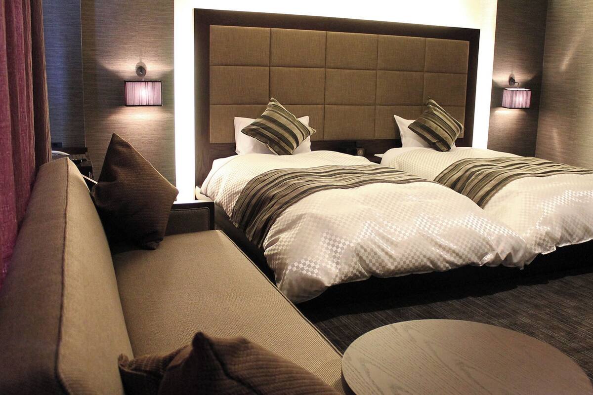 Een hotelkamer met een groot bed, een bank, een ronde tafel en twee wandlampen.