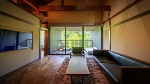 Un interior moderno con piso de madera, un sofá, una mesa y un balcón con vistas a zonas verdes.