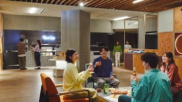 A modern interior with wooden ceiling beams, a bar area, and seating arrangements.