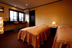 Habitación de hotel con dos camas, una ventana, un escritorio y una silla.