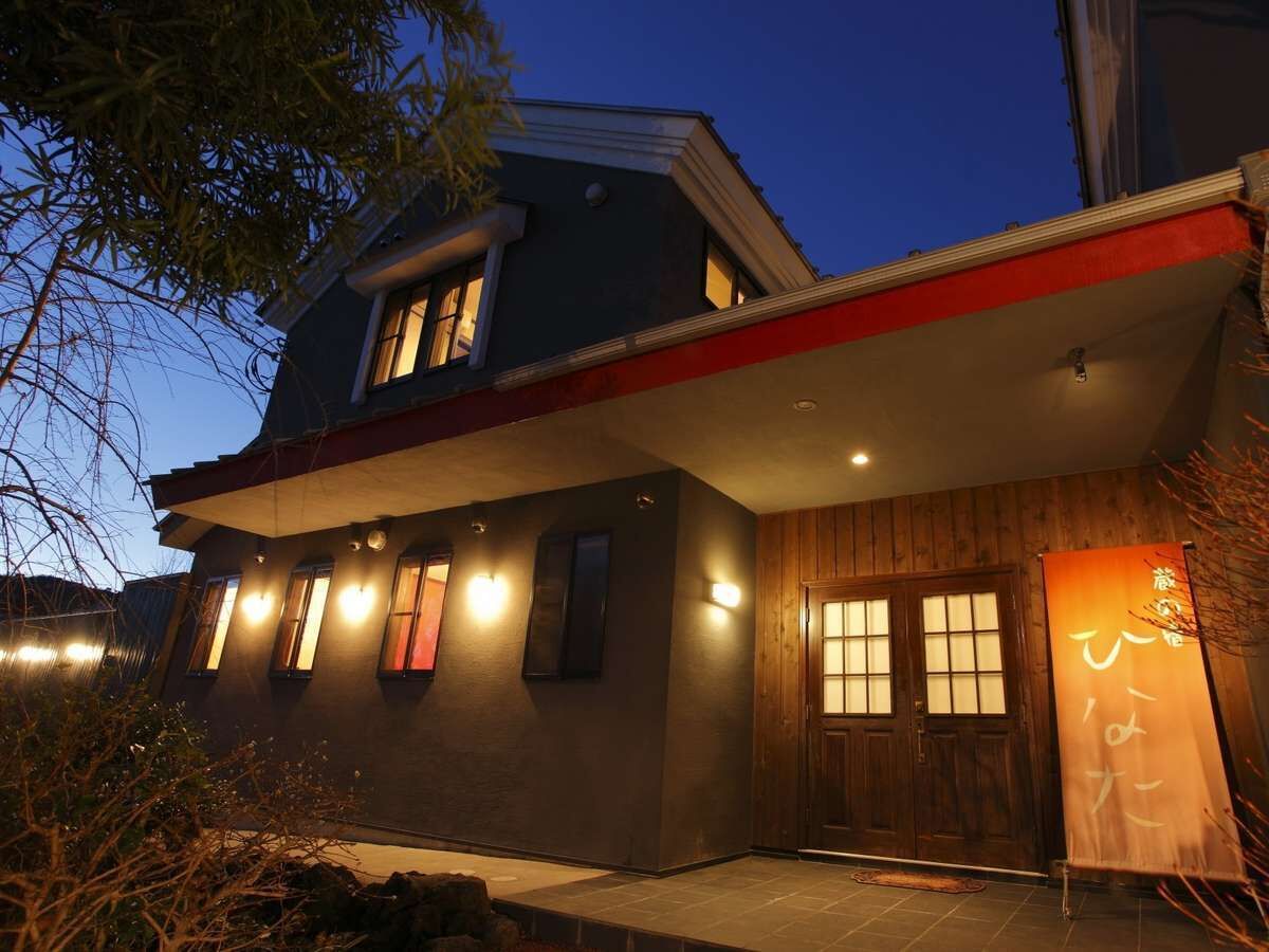 Una casa moderna con techo plano, varias ventanas y una puerta de madera.