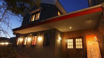 Una casa moderna con techo plano, varias ventanas y una puerta de madera.