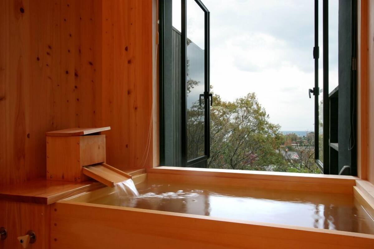 A wooden sauna with a view of trees and buildings.