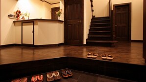 A wooden staircase leading to a landing with a dark wood floor, a reception desk, and a display of shoes. - Izukogen Onsen Kura no Yado Hinata (Ito)