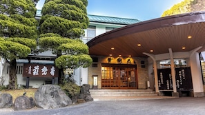 A traditional Japanese building with a wooden entrance and a signboard.