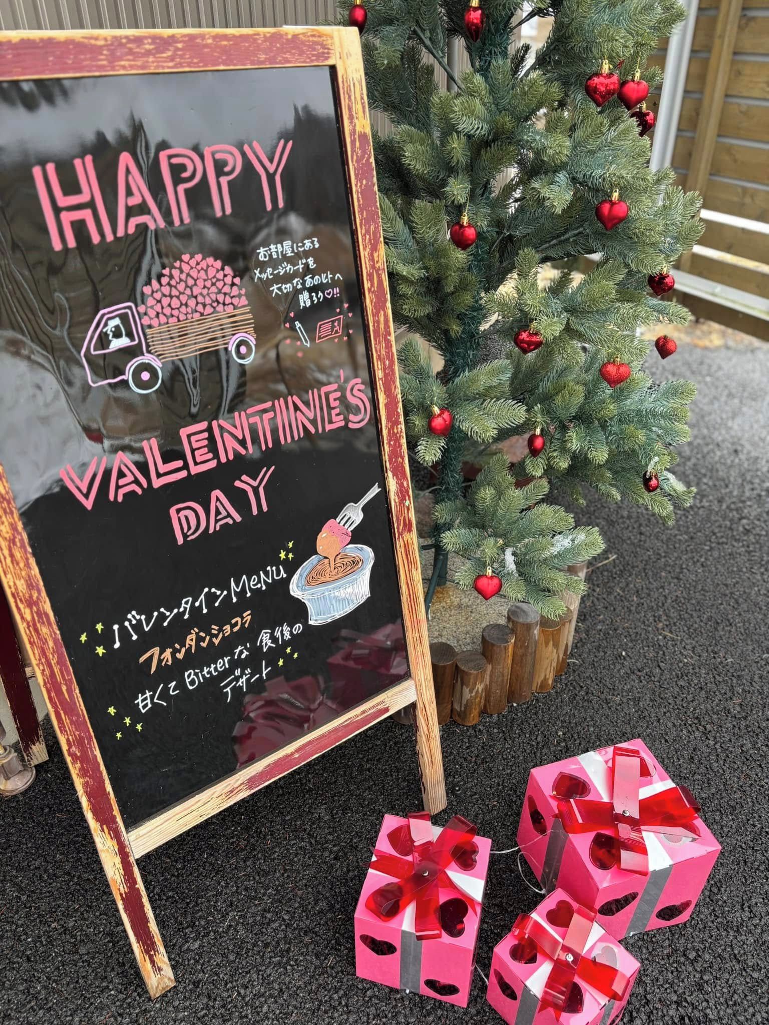 Un letrero de Día de San Valentín con un mensaje y un pequeño árbol de Navidad con adornos.