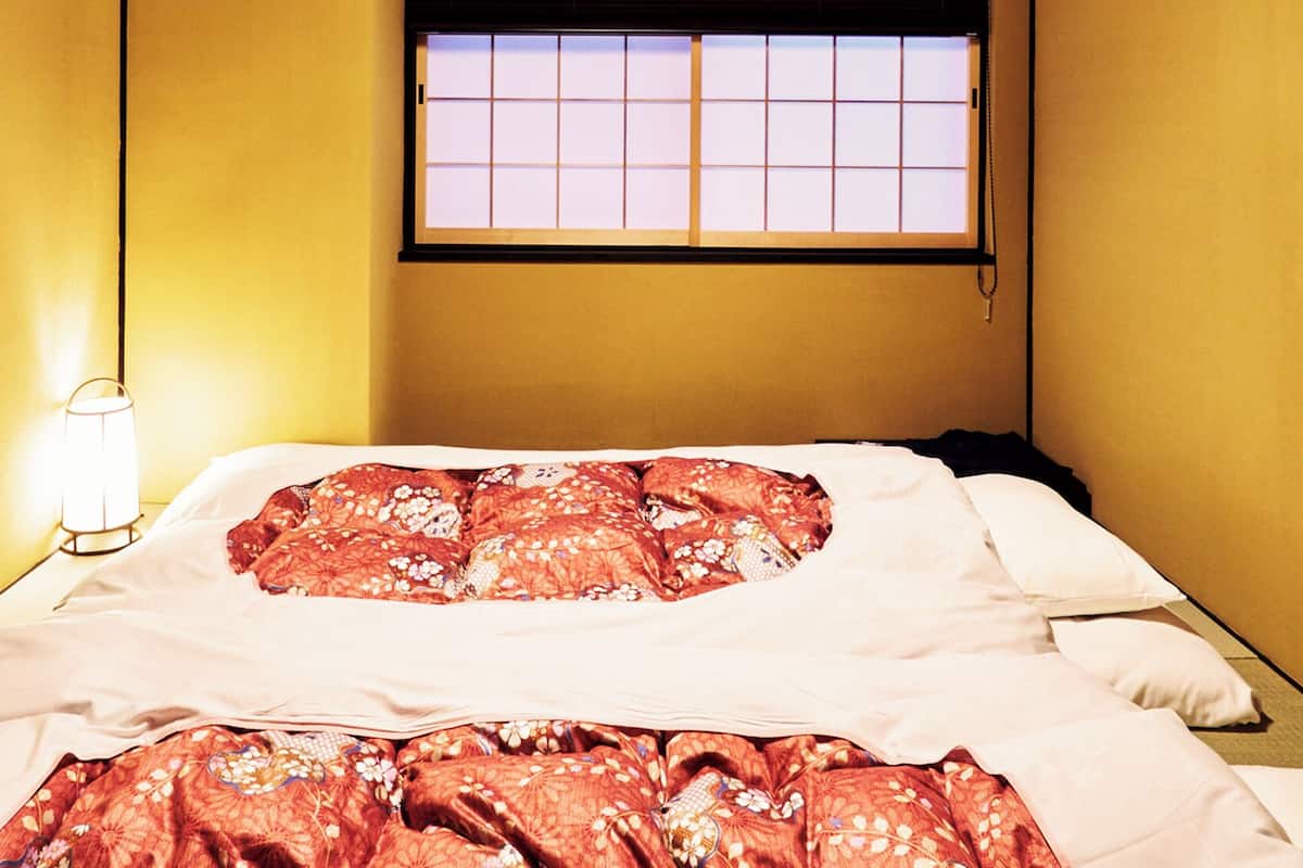 A hotel room with a bed, a nightstand, a lamp, and a window with a view.