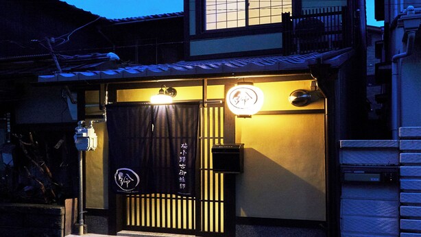 Un edificio tradizionale giapponese con un cancello nero, insegne illuminate e un piccolo ingresso.