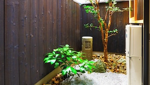 Una recinzione di legno, un piccolo albero, una struttura in pietra e un armadietto bianco in un giardino.
