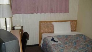 Habitación de hotel con cama, escritorio, teléfono y una silla.