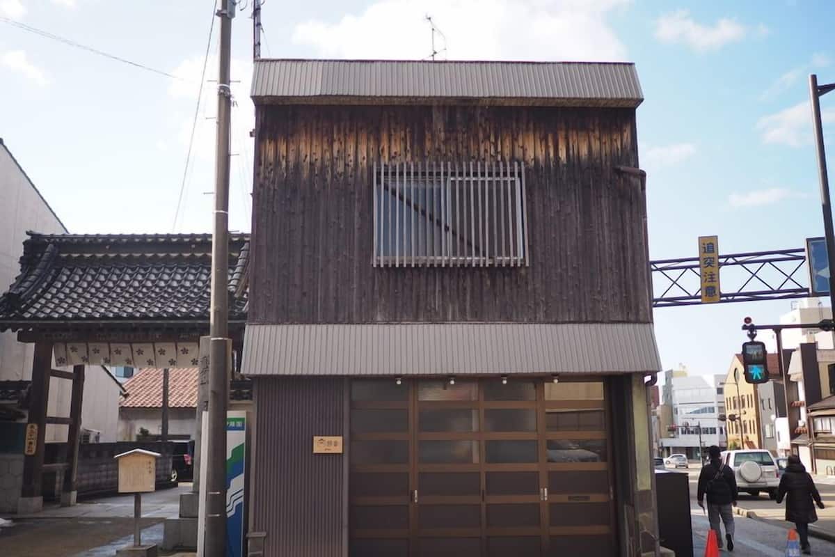 Ein Gebäude mit einer großen Garagentür, einem kleinen Fenster und einem traditionellen Ziegeldach.