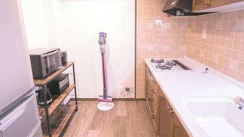 A compact kitchen with a microwave, stove, and cleaning equipment.