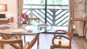 Un coin repas avec une table en verre, des chaises en bois et un vase de fleurs.