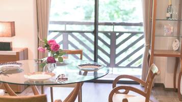 A dining area with a glass table, wooden chairs, and a vase of flowers.