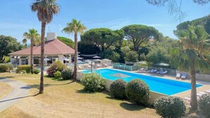 A pool area with lounge chairs, palm trees, and a building with a red roof. - Prestige Relax, private Bastidons and exclusive setting on 4 hectares with swimming pool (Fréjus)