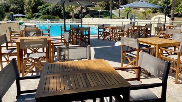 An outdoor pool area with wooden tables and chairs, umbrellas, and a view of the pool and surrounding greenery. - Prestige Relax, private Bastidons and exclusive setting on 4 hectares with swimming pool (Fréjus)