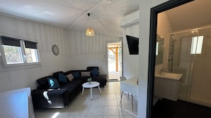 A compact living space with a sofa, a small round table, and a TV mounted on the wall. - Prestige Relax, private Bastidons and exclusive setting on 4 hectares with swimming pool (Fréjus)