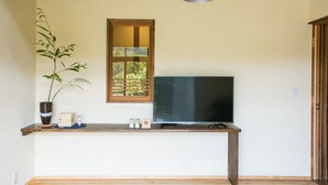 A room with a wooden desk, a television, a potted plant, a window, and a hanging lamp. - Guest House Mate Mate (Odai)