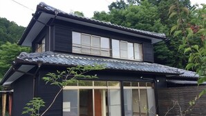 A two-story building with a traditional Japanese architectural style, featuring a tiled roof and sliding glass doors. - Guest House Mate Mate (Odai)