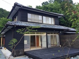 Um edifício de dois andares com arquitetura japonesa tradicional, com telhado de telhas e portas de correr de vidro.