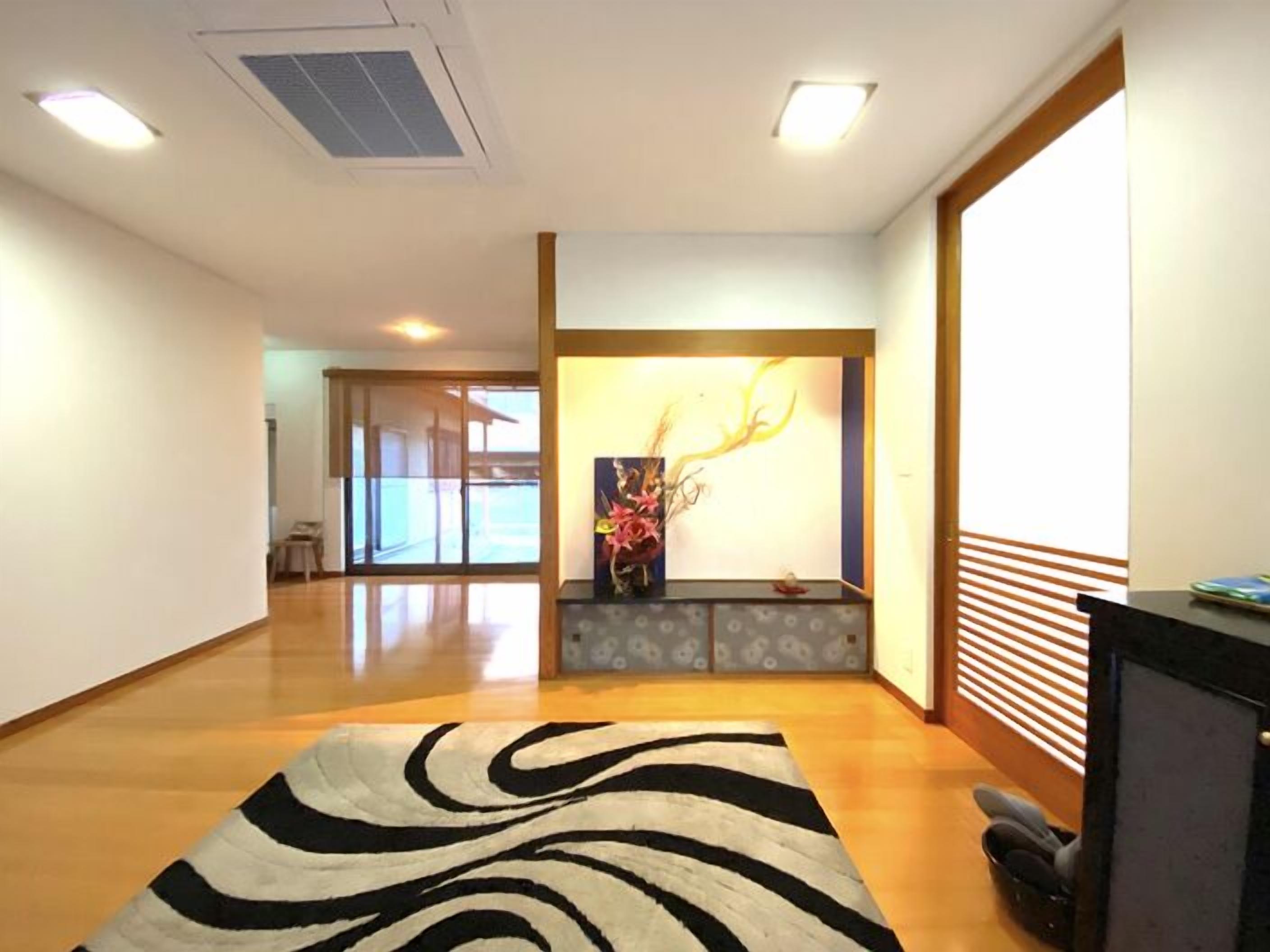 A spacious hallway with a zebra-patterned rug, a reception desk with a vase of flowers, and a sliding glass door leading to an outdoor area.