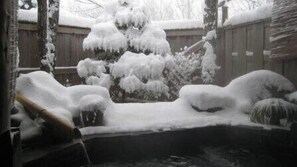 A snow-covered outdoor area with a wooden fence, a snow-covered tree, and a pond. - Pension Schooner (Nasu)