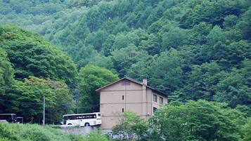 A building with a simple, rectangular structure, surrounded by dense forest.