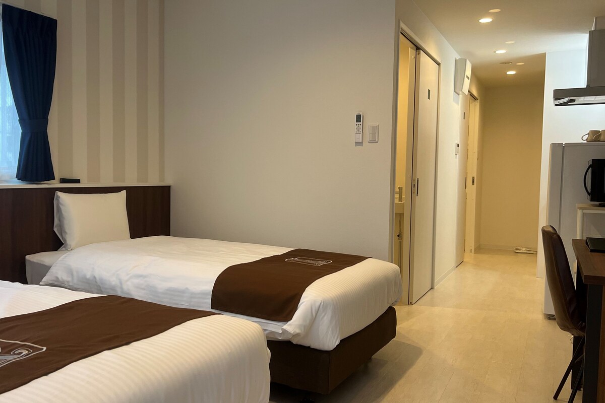 A hotel room with two beds, a desk, a microwave, and a coffee maker.