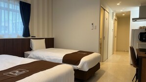 Et hotelværelse med to senge, et skrivebord, en mikrobølgeovn og en kaffemaskine.