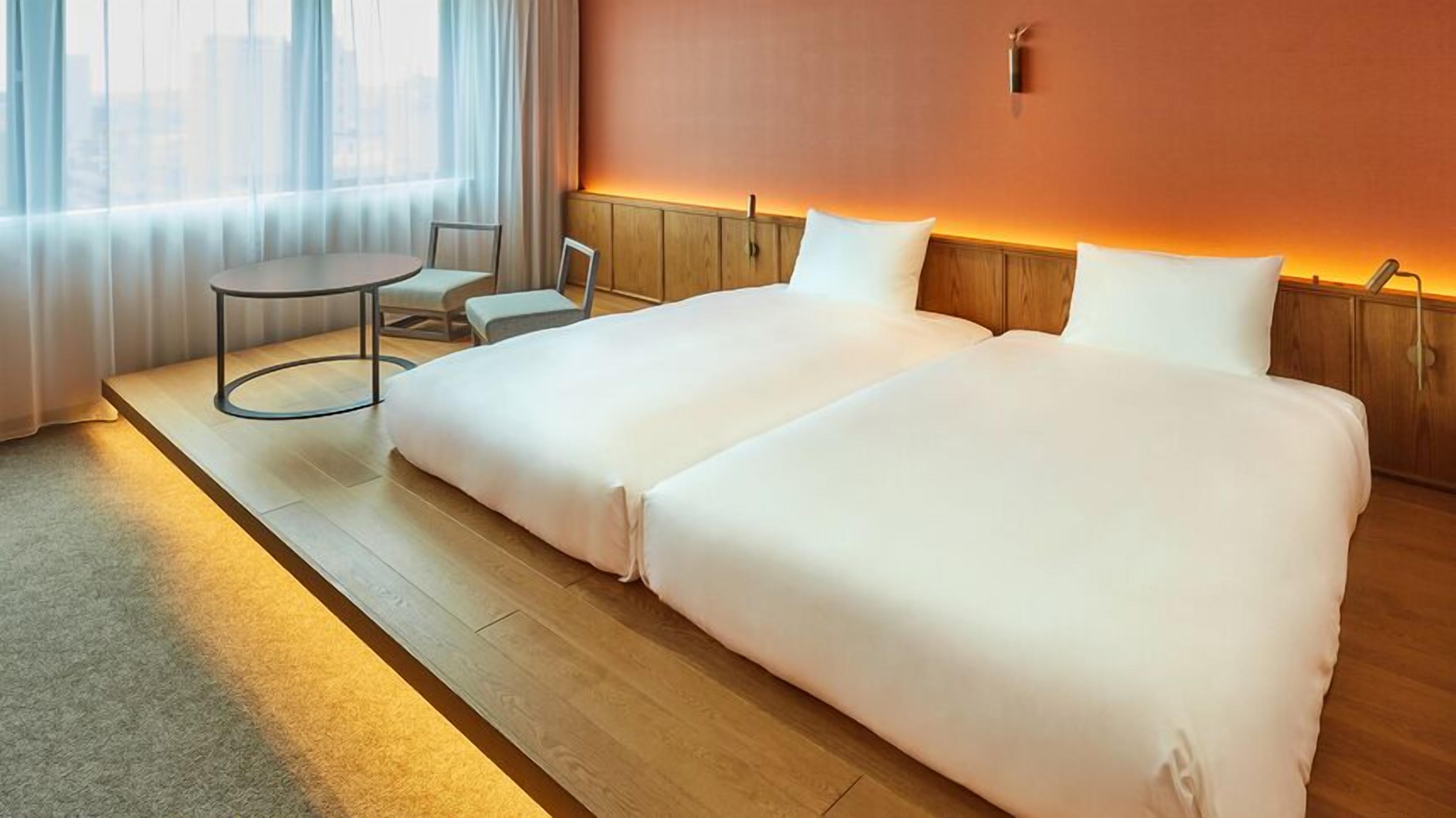 Une chambre d’hôtel avec un lit, une petite table et une chaise.