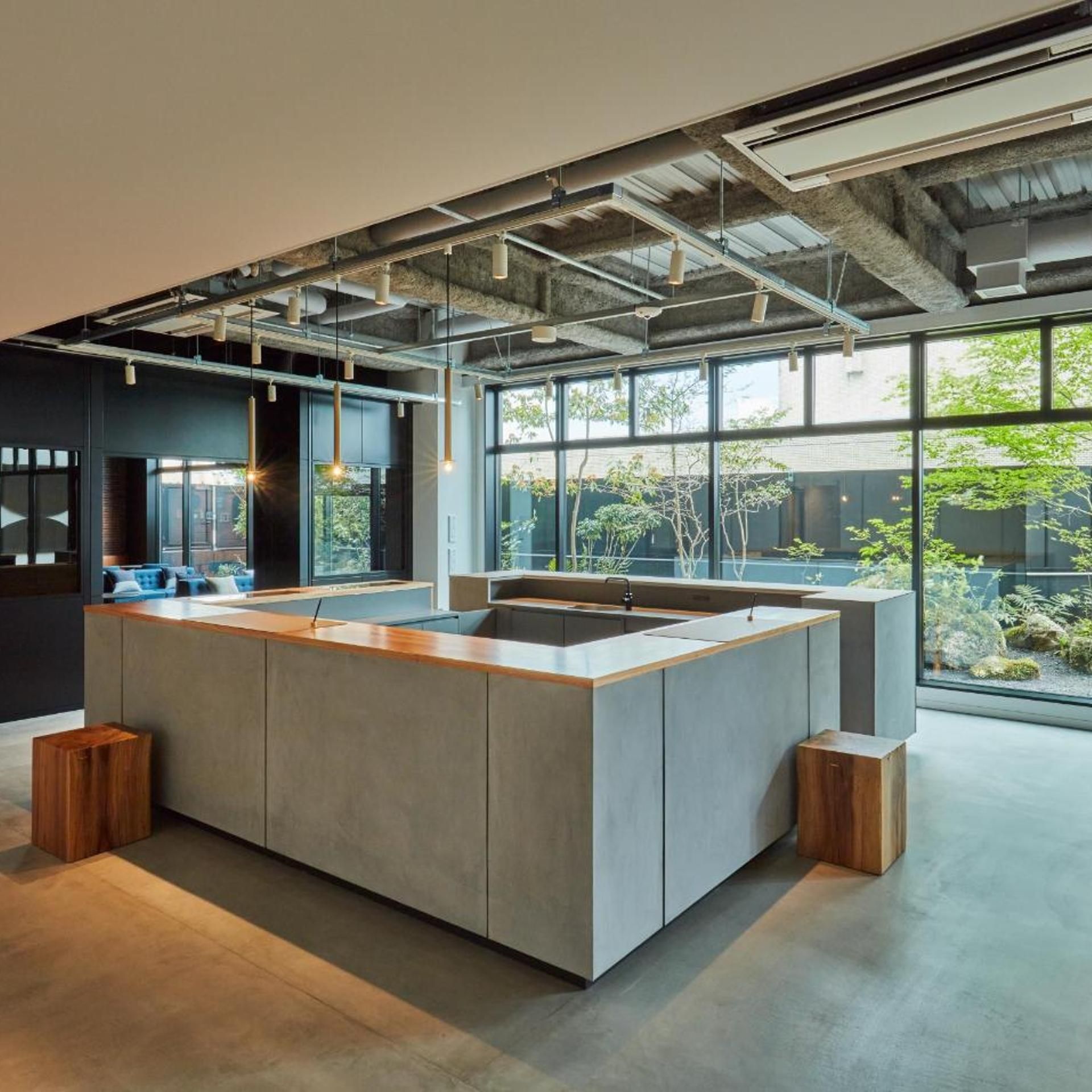 A modern kitchen with a large island, large windows, and exposed ductwork.