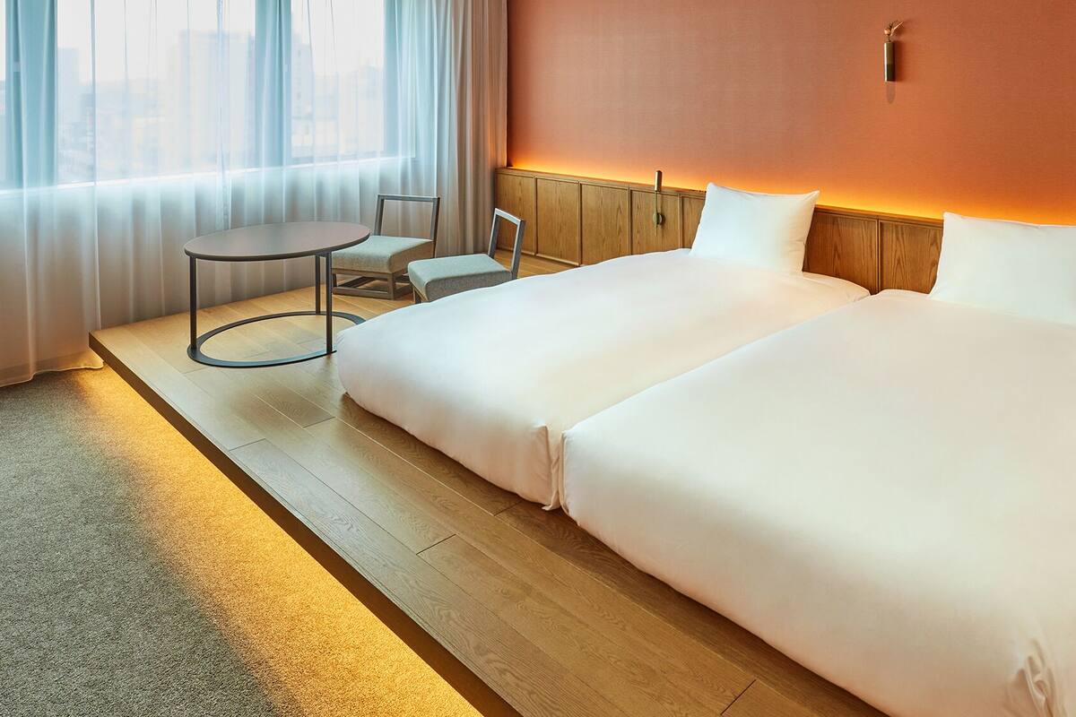 Een hotelkamer met een groot bed, een klein rond tafeltje en een stoel.