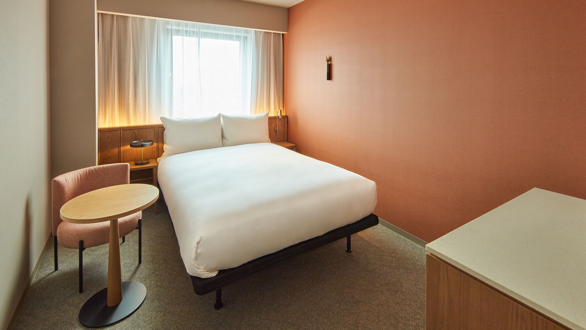 Une chambre d’hôtel avec un lit, un bureau, une chaise et une table de chevet.