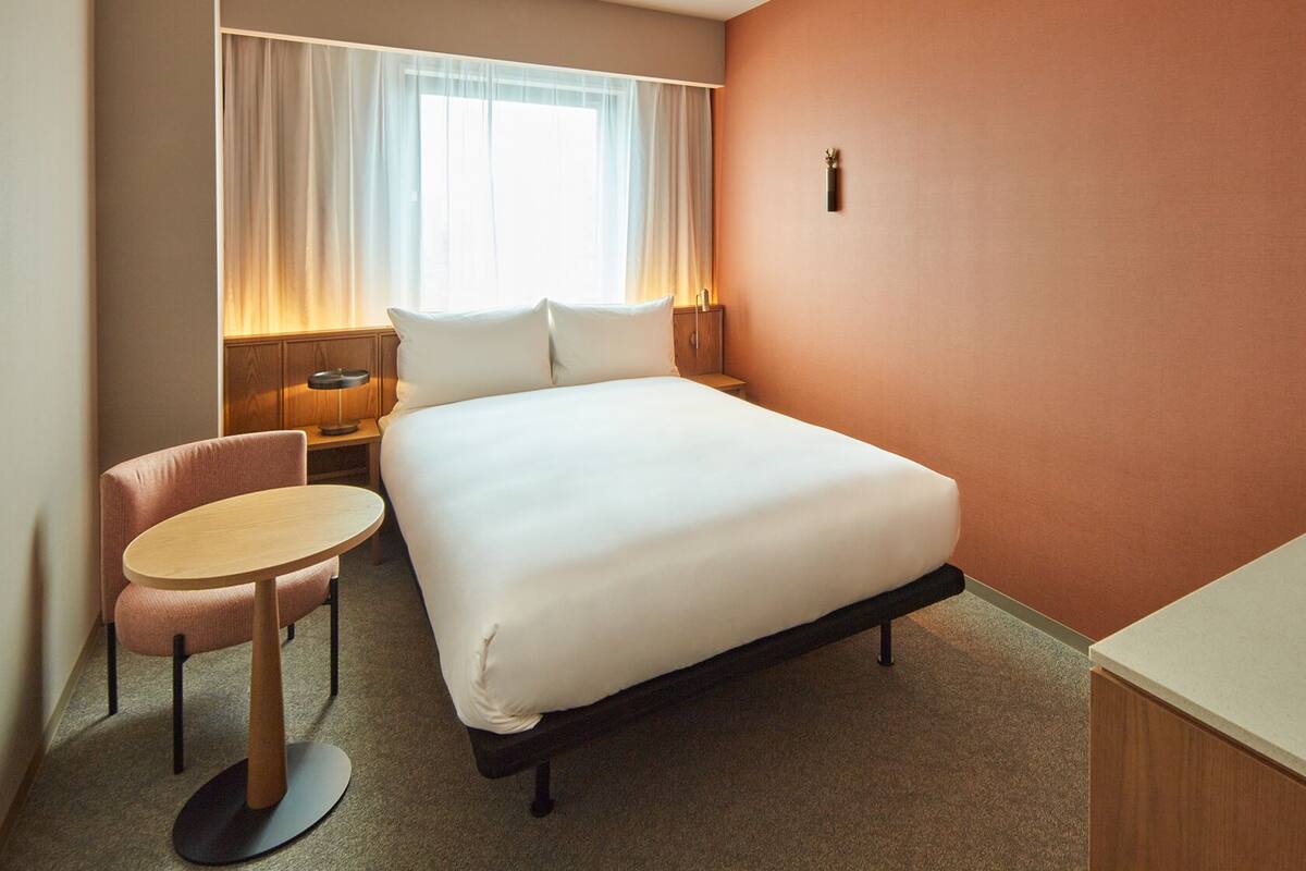 Een hotelkamer met een bed, een bureau, een stoel en een nachtkastje.