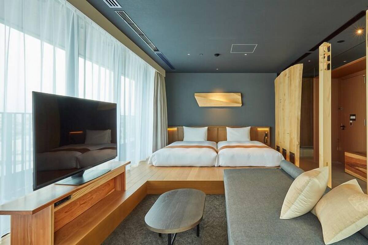 Een moderne hotelkamer met een groot bed, een bank, een televisie en een houten garderobe.