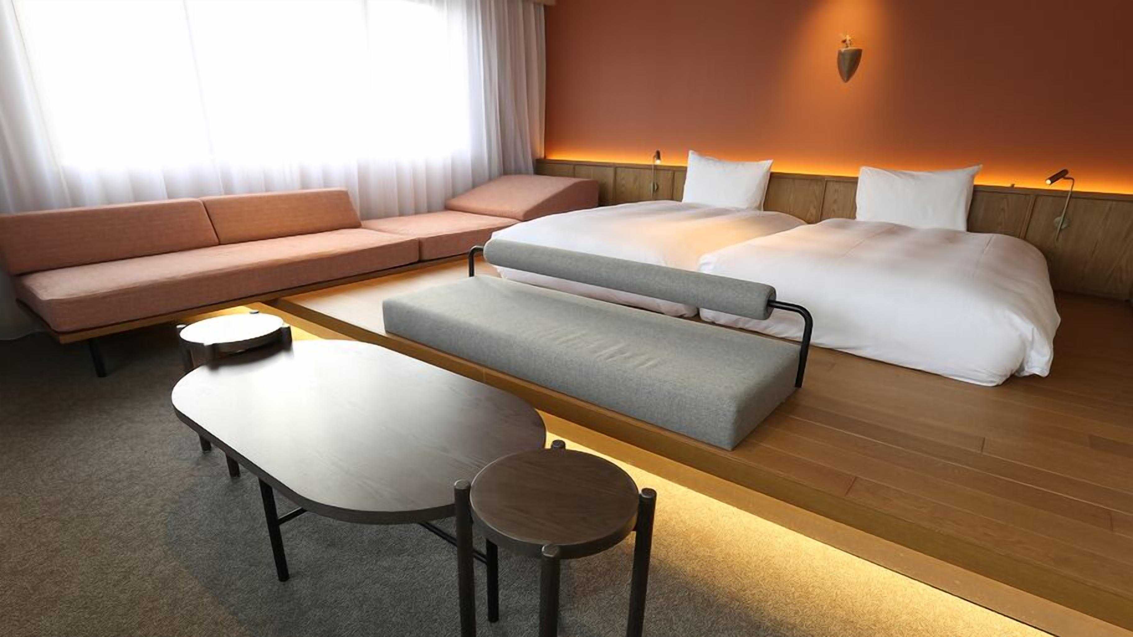 Une chambre d’hôtel moderne, équipée d’un canapé, d’un lit, d’un banc et d’une petite table.