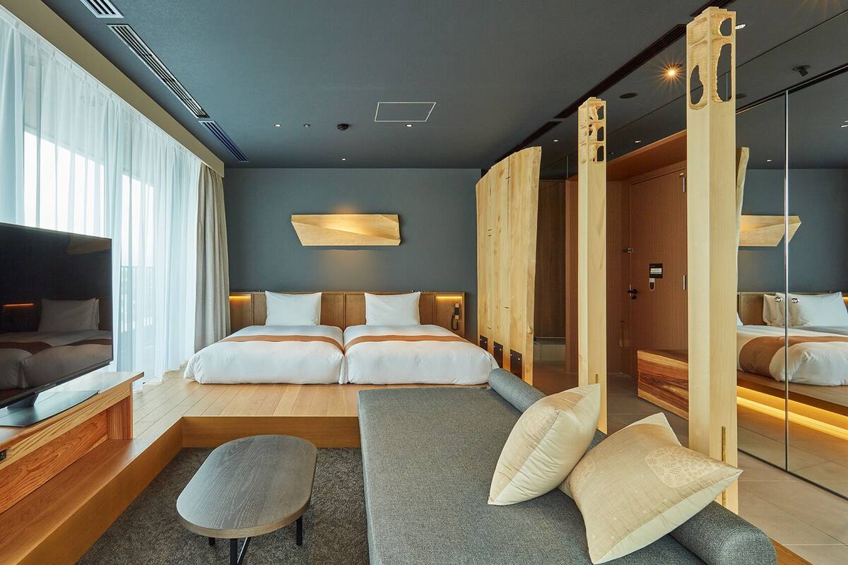 Een moderne hotelkamer met een groot bed, een bank, een televisie en een houten garderobe.