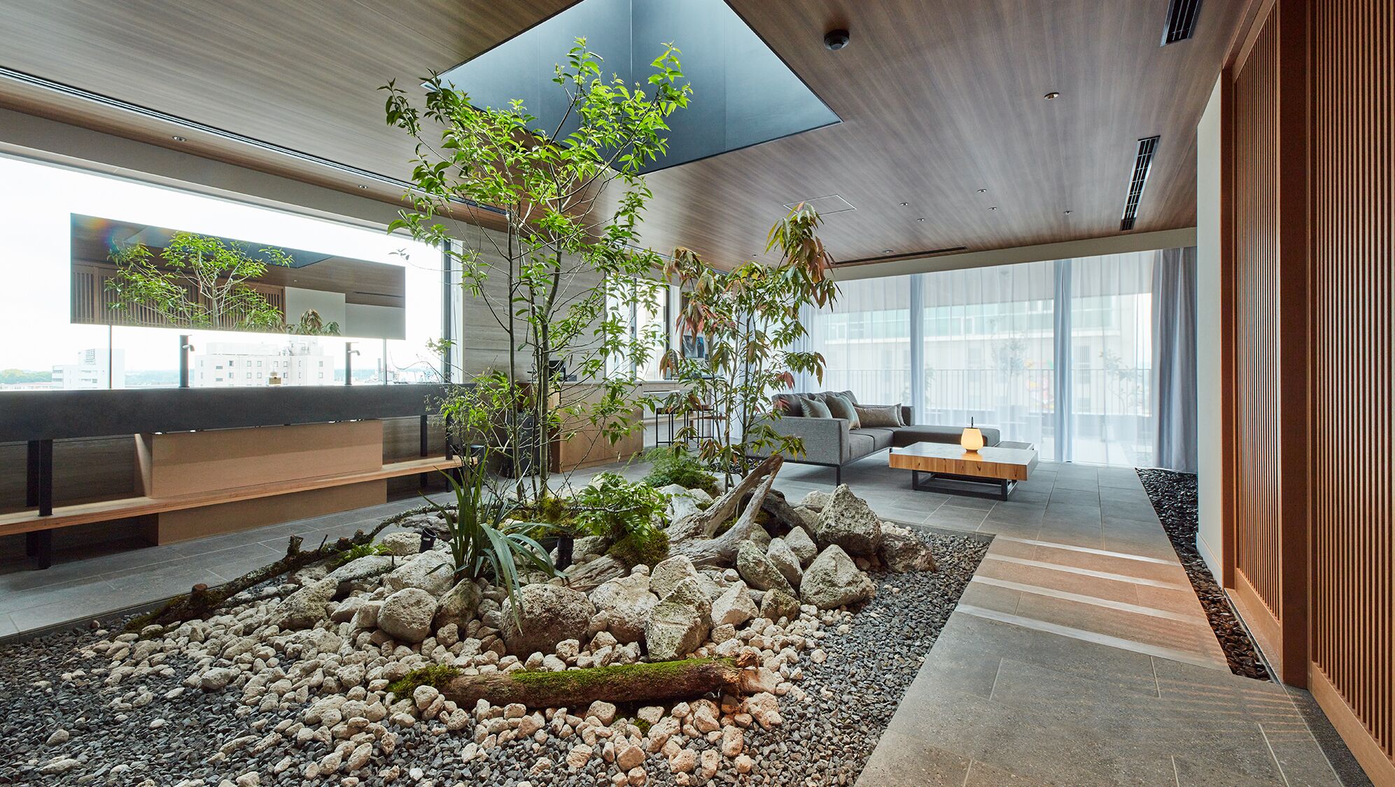 Un intérieur moderne avec un jardin de rocaille central, un espace salon et de grandes fenêtres.