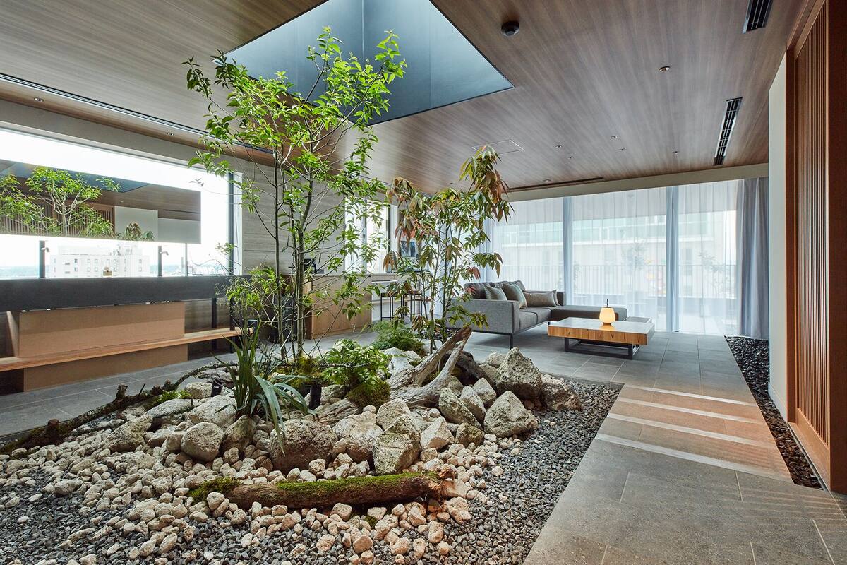 Een modern interieur met een centrale rotstuin, zithoek en grote ramen.