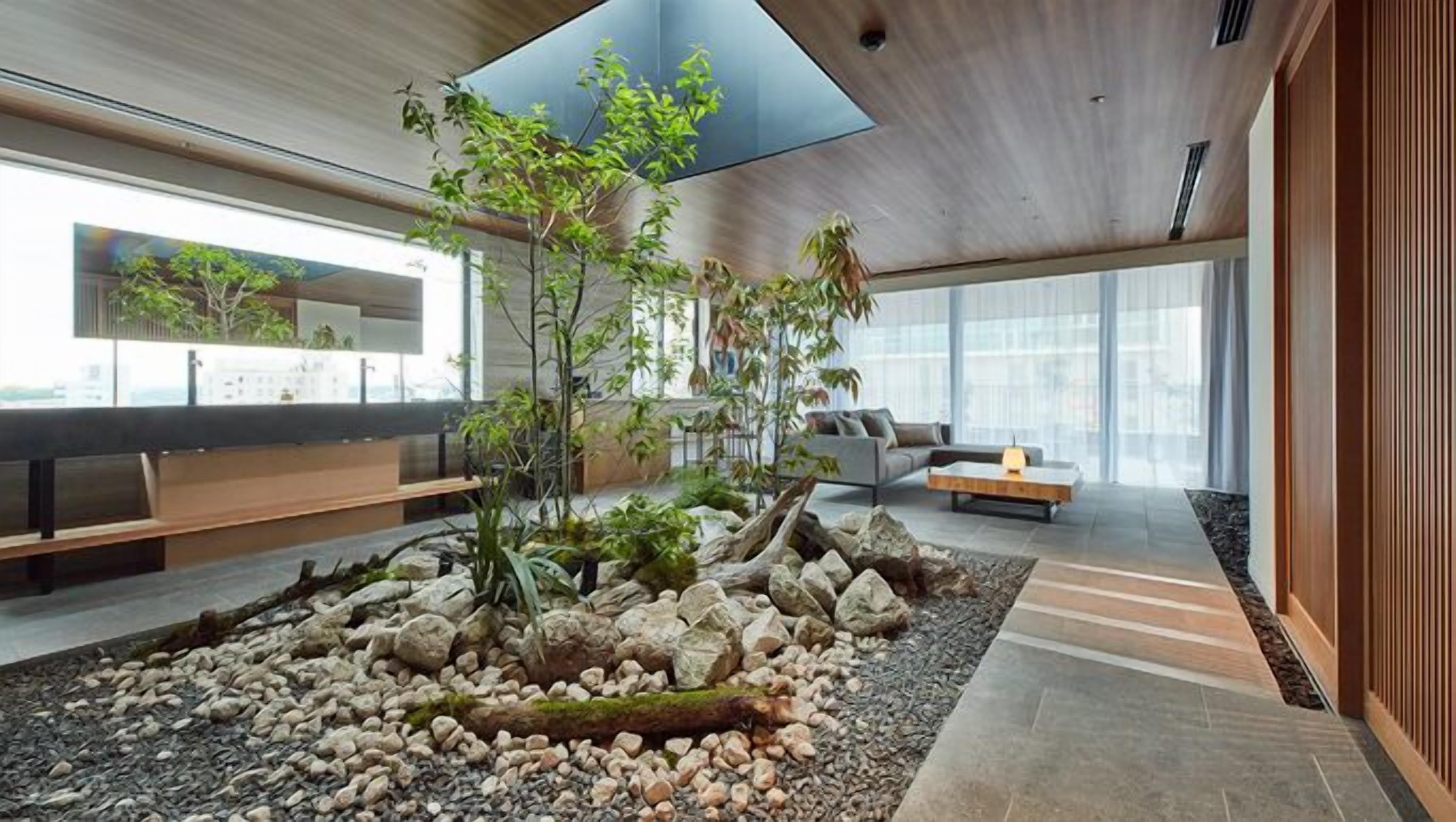 Un intérieur moderne avec un jardin de rocaille central, un espace salon et de grandes fenêtres.