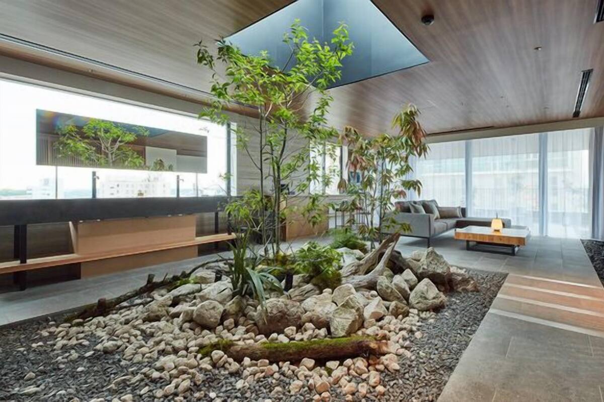 Een modern interieur met een centrale rotstuin, een zithoek en grote ramen.