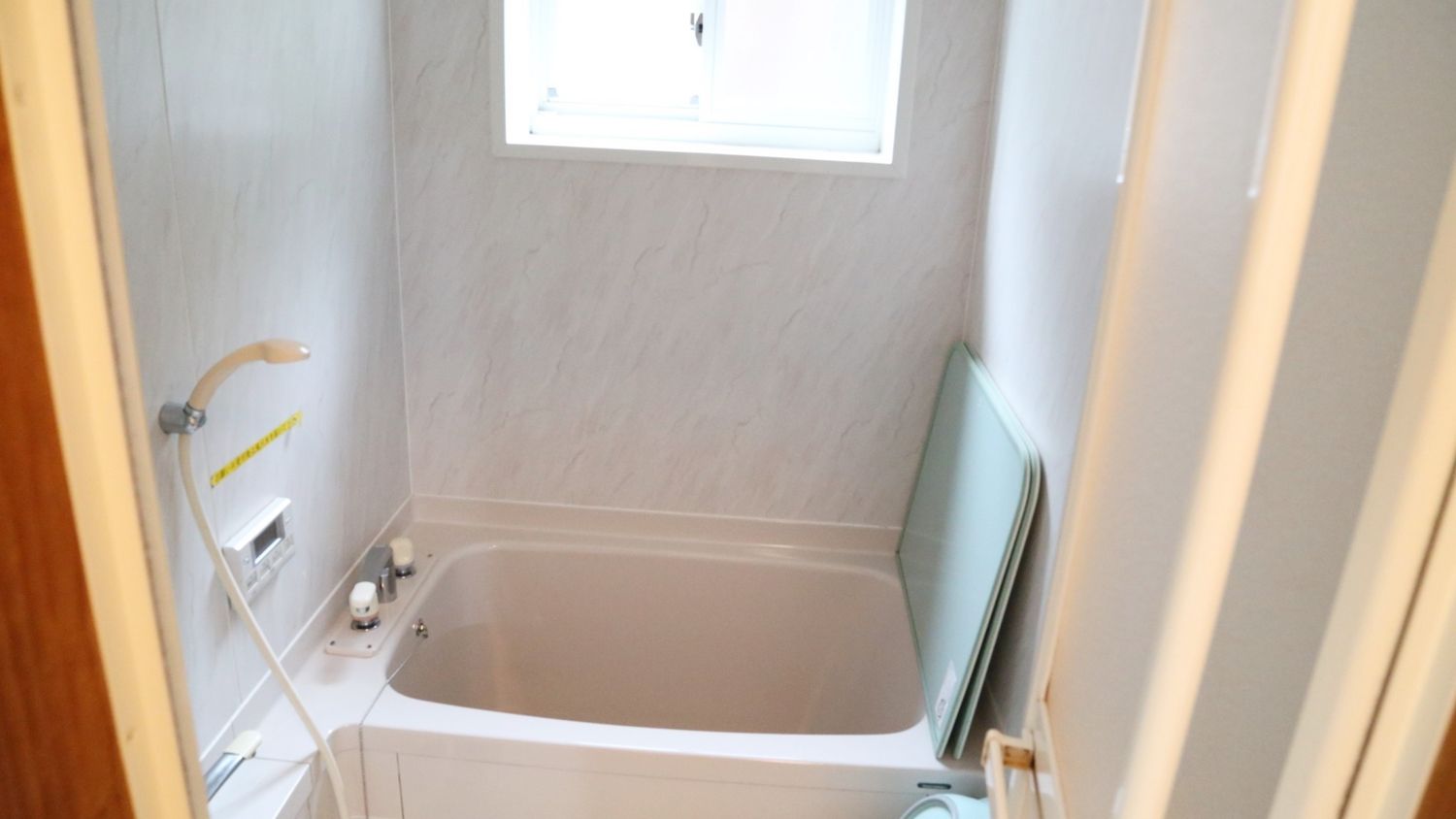 A bathroom with a bathtub, a window, and a towel rack.