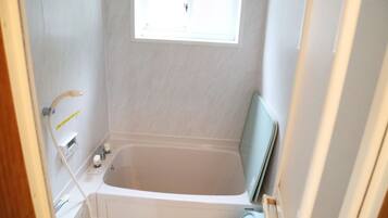 A bathroom with a bathtub, a window, and a towel rack.