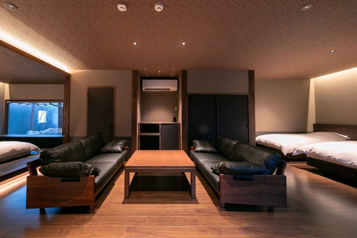 A hotel room with a sofa bed, a wooden coffee table, a TV, and a wardrobe.