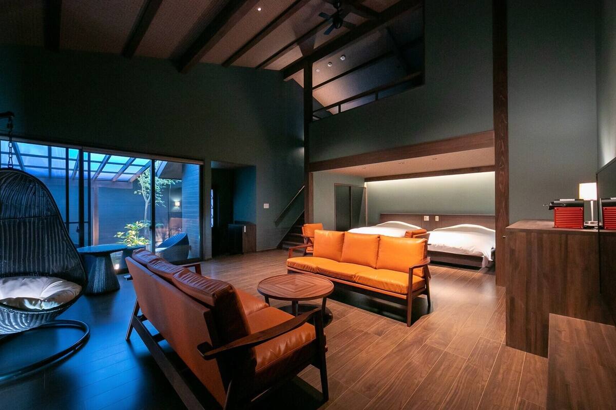 Ein modernes Hotelzimmer mit einer Schlafcouch, einem Sessel, einem Bett und einem Schreibtisch.