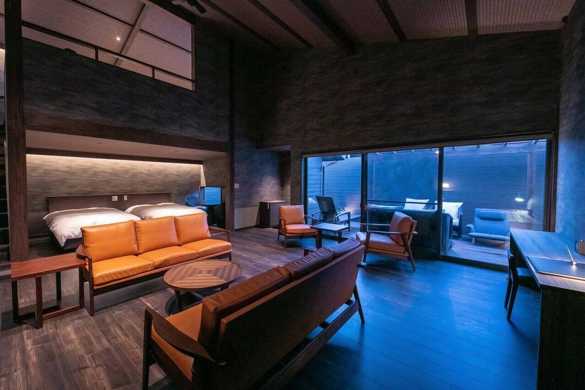 Ein modernes Interieur mit einer Couch, Sesseln, einem kleinen Tisch und einem Bett.