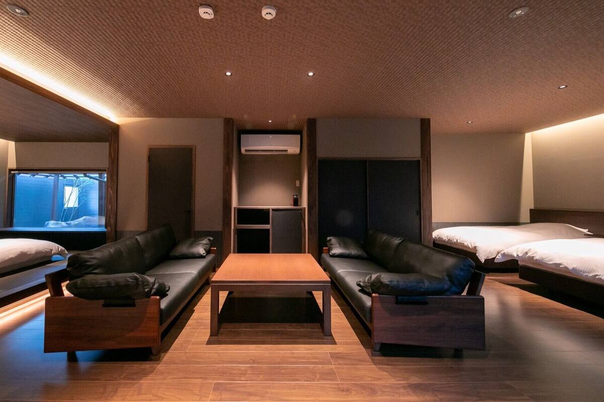 Ein Hotelzimmer mit einer Couch, einem Couchtisch, einem Fernseher und zwei Betten.