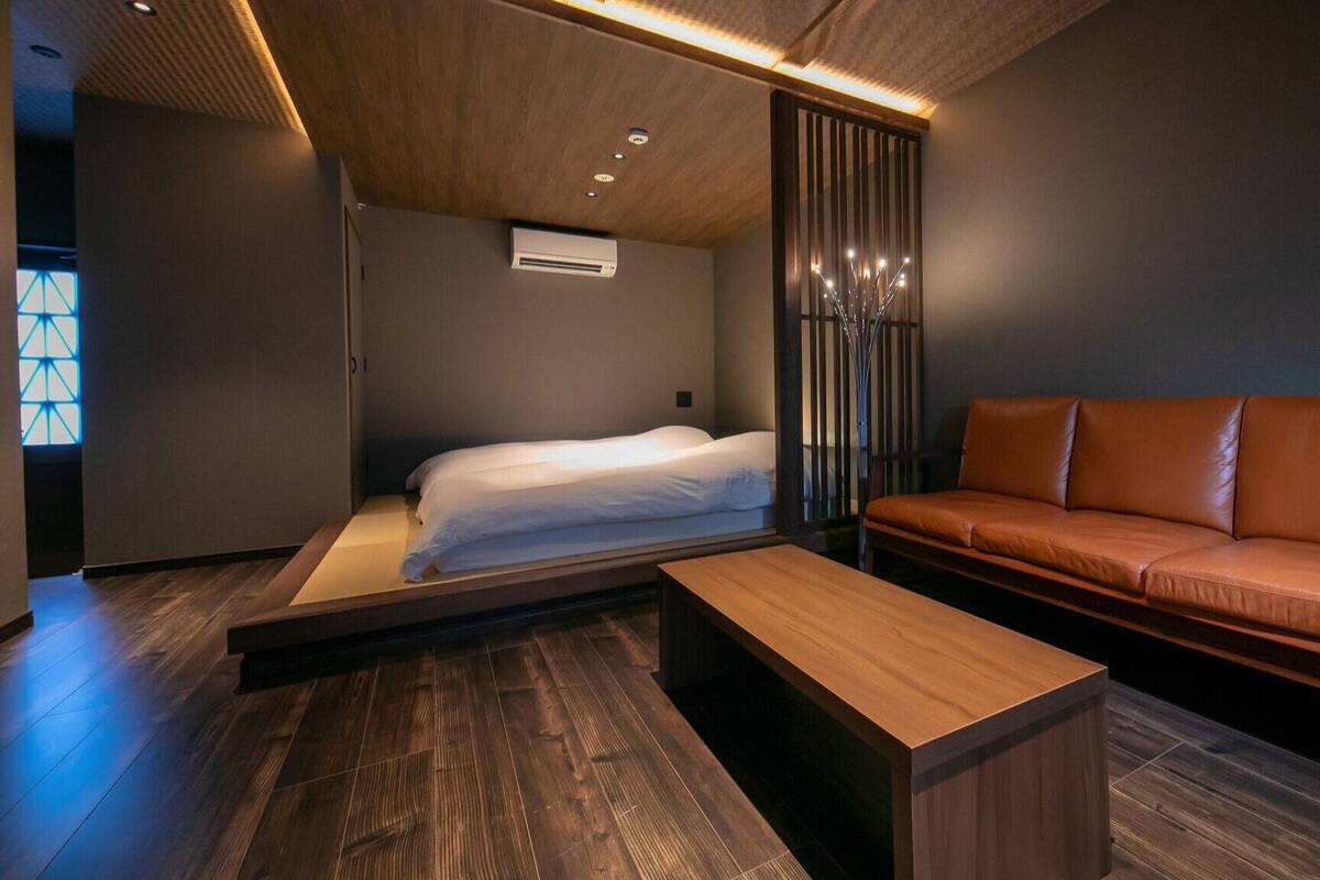 Ein modernes Zimmer mit einem Bett, einer Couch, einem Holztisch und einer dekorativen Lampe.