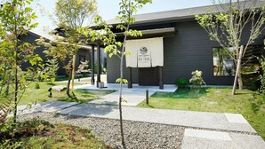 A modern building with a garden entrance, a signboard, and a pathway leading to the building. - Onsen Garden Yumoto Ann Kiyohime (Kirishima)