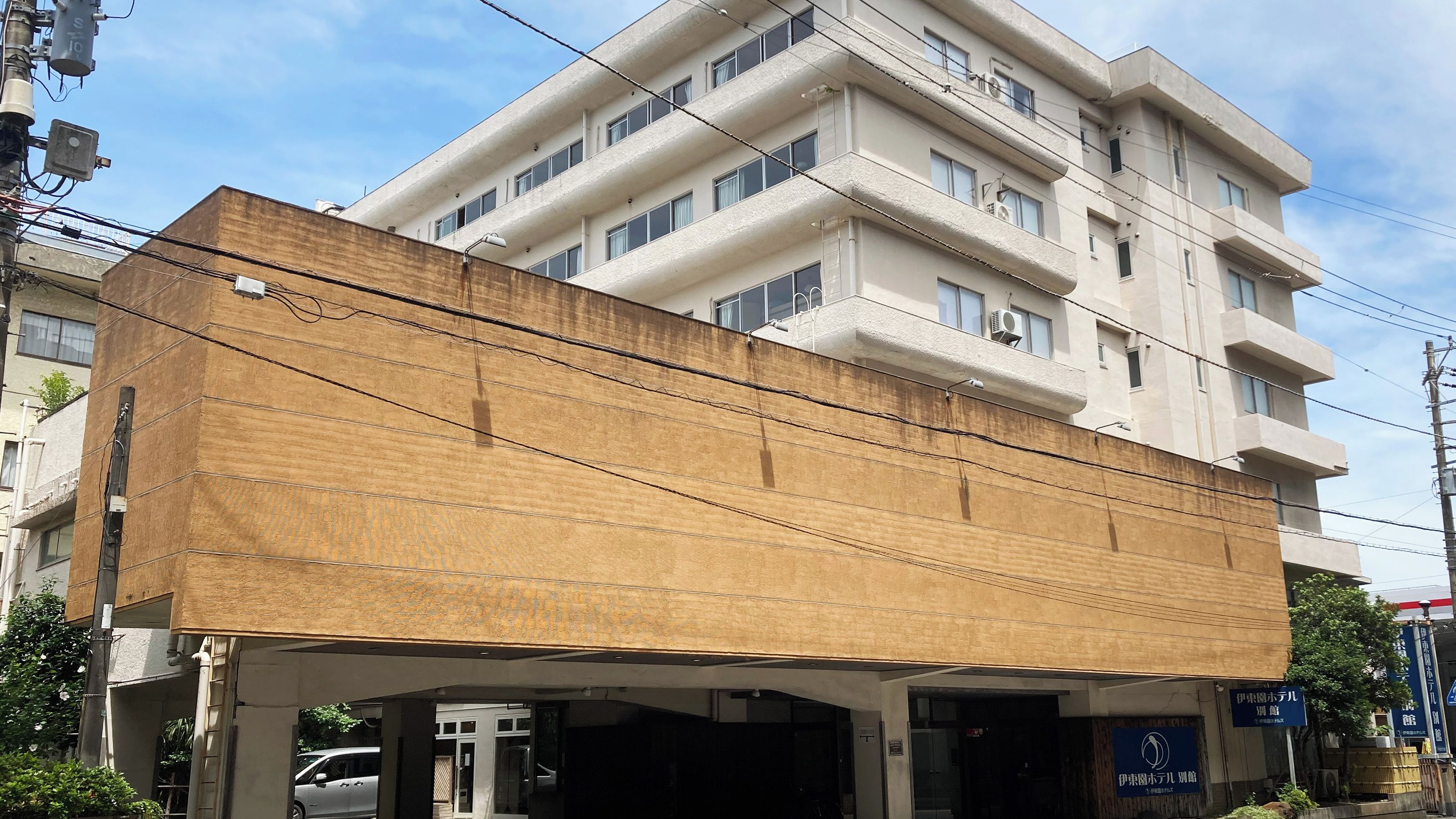 A multi-story building with a flat facade, multiple windows, and visible electrical wiring.